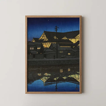 Hasui Kawase woodblock print of the Kabukiza theatre at night, its gabled roofs lit gold and reflected in the still river below.