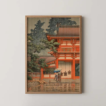 Hasui Kawase woodblock print of Kasuga Shrine in Nara in the rain, two figures sheltering under an umbrella beneath the vermilion gate.