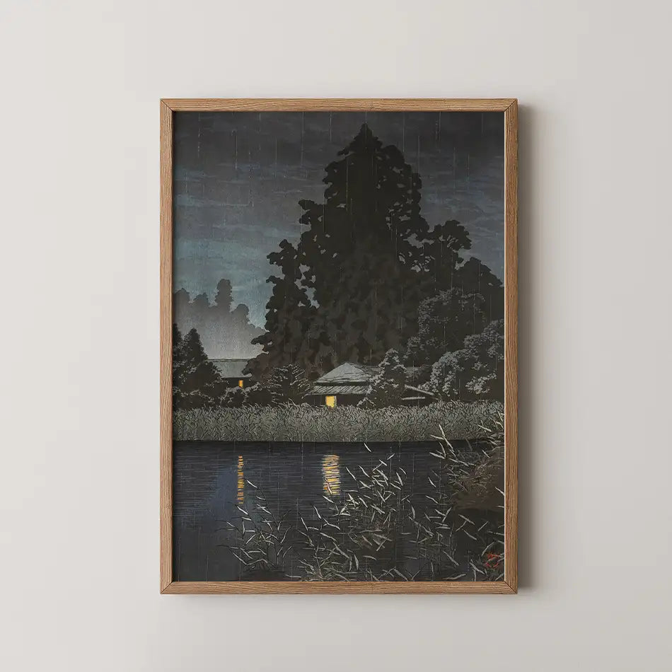 Hasui Kawase woodblock print of Rain at Omiya, silhouetted trees and reeds beside a dark lake with two lit windows glowing in the rain.