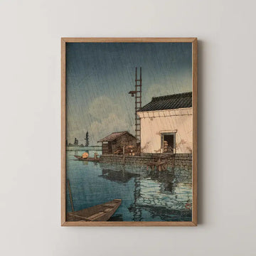 Hasui Kawase woodblock print of Rain at Ushibori, a lakeside storehouse with a ladder against its wall and a boat crossing the water in the rain.