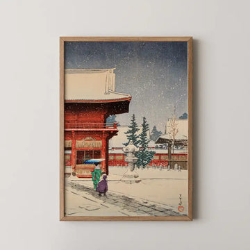 Hasui Kawase woodblock print of Snow at Nezu Gongen Shrine, a red shrine gate with two figures passing beneath falling snow.