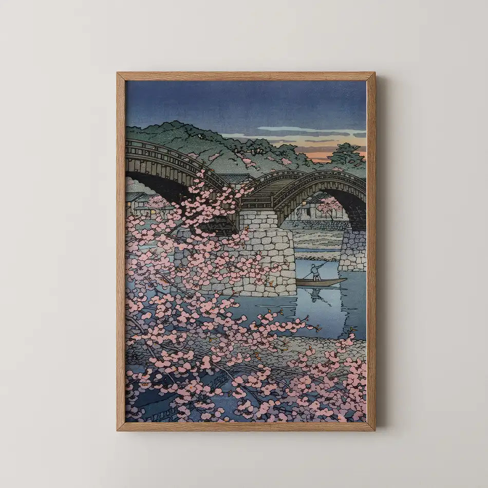 Hasui Kawase woodblock print of Spring Evening at Kintai Bridge, cherry blossom in the foreground with a boatman crossing beneath the wooden arches at dusk.