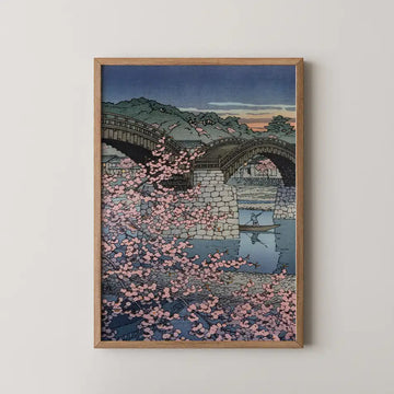 Hasui Kawase woodblock print of Spring Evening at Kintai Bridge, cherry blossom in the foreground with a boatman crossing beneath the wooden arches at dusk.
