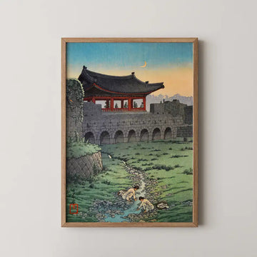 Hasui Kawase woodblock print of the old fortress gate at Suwon, Korea, at dusk, with figures washing clothes in a stream below.