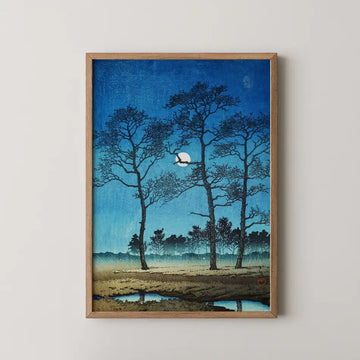 Hasui Kawase woodblock print of Winter Moon at Toyamagahara, bare trees silhouetted against a deep blue sky around a pale full moon.
