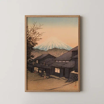 Hasui Kawase woodblock print of Yui, Suruga, a village street beneath a glowing dusk sky and snow capped Mount Fuji.