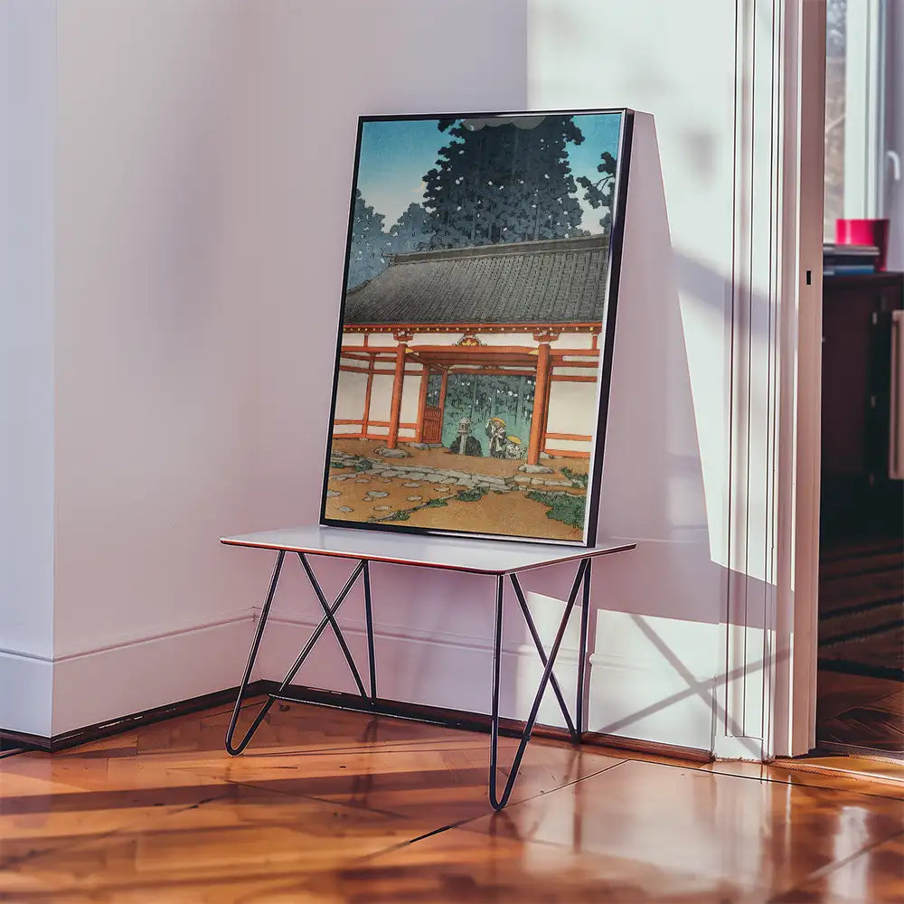 Painting of a traditional Japanese building with a picturesque garden, displayed on a table in a room with natural light.