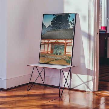 Painting of a traditional Japanese building with a picturesque garden, displayed on a table in a room with natural light.