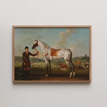 Painting of a man in a riding outfit holding a horse with a saddle, set in a landscape with a hunt scene in the background, framed in wood.