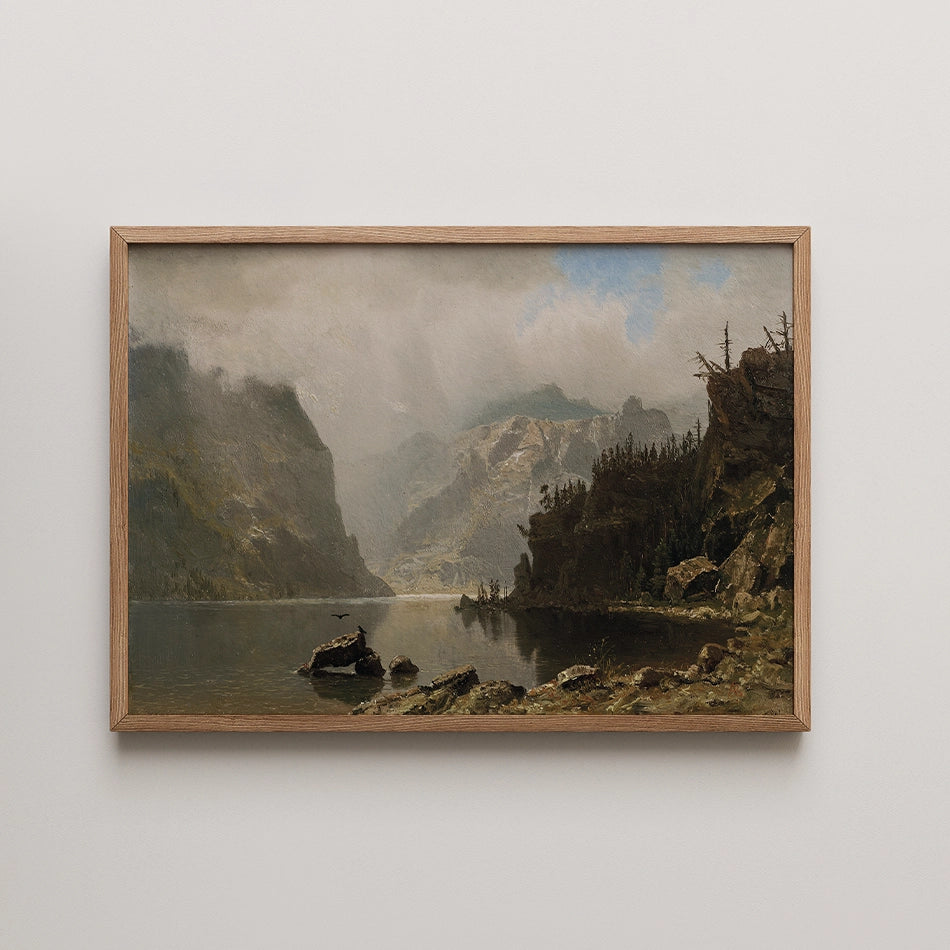 Mountain landscape painting in a wooden frame, depicting a serene lake surrounded by hills and clouds.