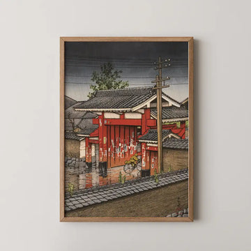 Japanese-inspired painting of a red building with a bicycle, framed in wood, depicting a rainy scene with muted colors and traditional architecture.