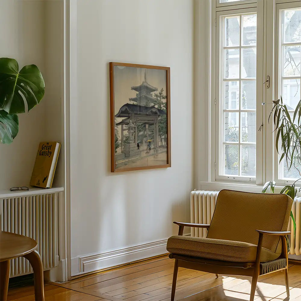 Painting of a traditional Japanese pagoda framed and displayed in a modern living room with a wooden chair and potted plant.