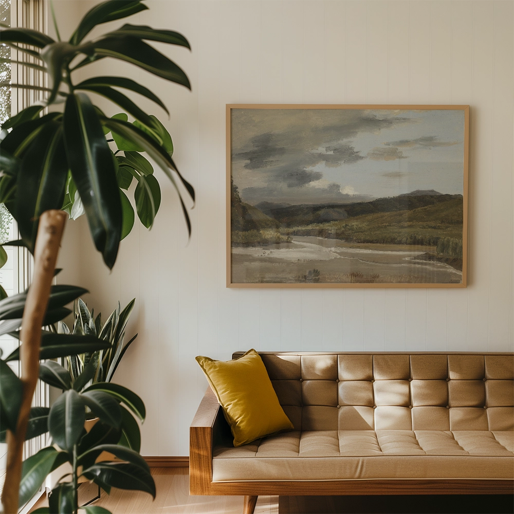 A landscape painting featuring a river and mountains, framed and hanging on a wall above a beige sofa with a yellow pillow, surrounded by indoor plants.