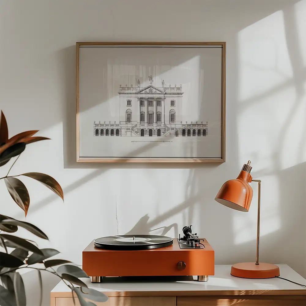 Artistic wall art featuring an architectural illustration in a framed setting above a stylish record player and a contemporary orange desk lamp.