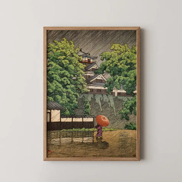 Framed artwork depicting a woman in a purple kimono walking with an umbrella in a rainy landscape featuring lush greenery and traditional architecture.
