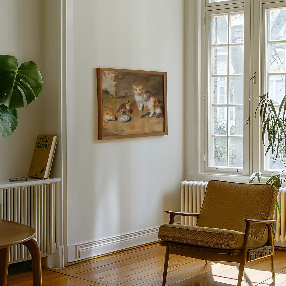 Painting of three cats interacting with a plate of food, mounted on a light-colored wall in a cozy interior setting with a chair, bookshelf, and a plant.