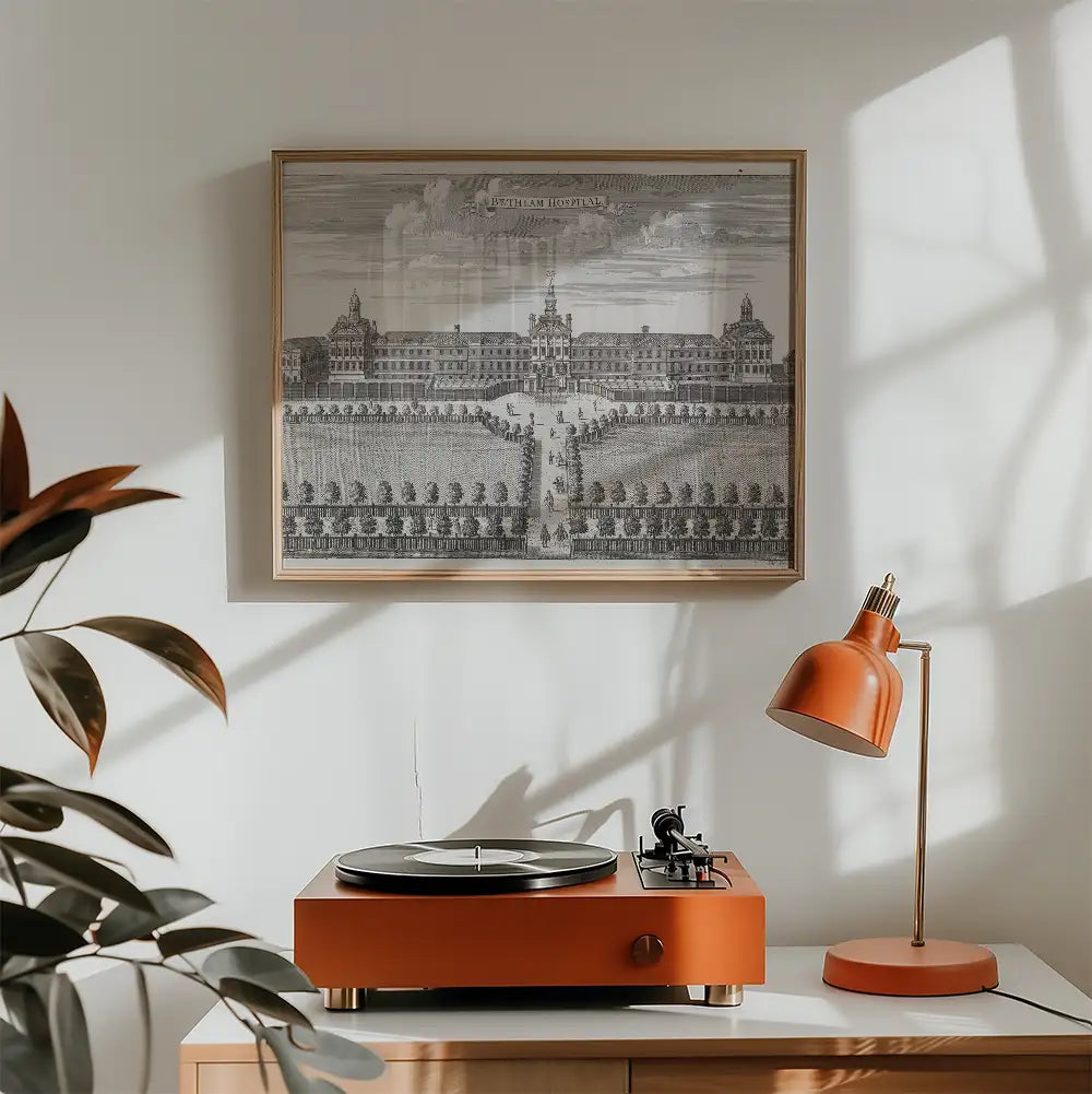 Vintage print of Bethlem Hospital framed above an orange turntable and lamp in a modern living space.