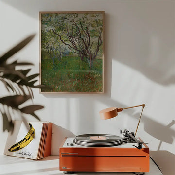 Painting of trees in a green field displayed above a record player in a modern interior setting.