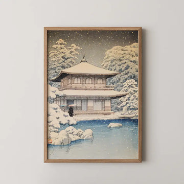 Framed painting of a snow-covered traditional Japanese building surrounded by trees and a serene pond