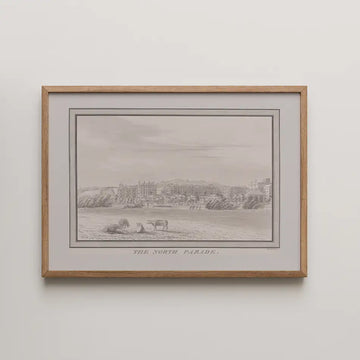 Framed monochrome illustration titled "The North Parade," depicting a coastal scene with cows and buildings in the background.