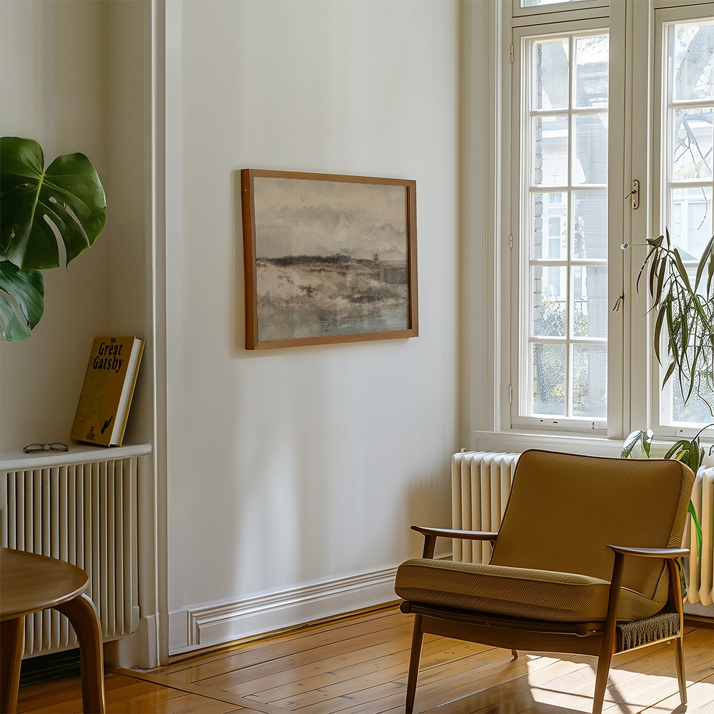 Abstract landscape painting framed in wood, displayed on a light-colored wall in a cozy living room setting with a modern chair and plants.