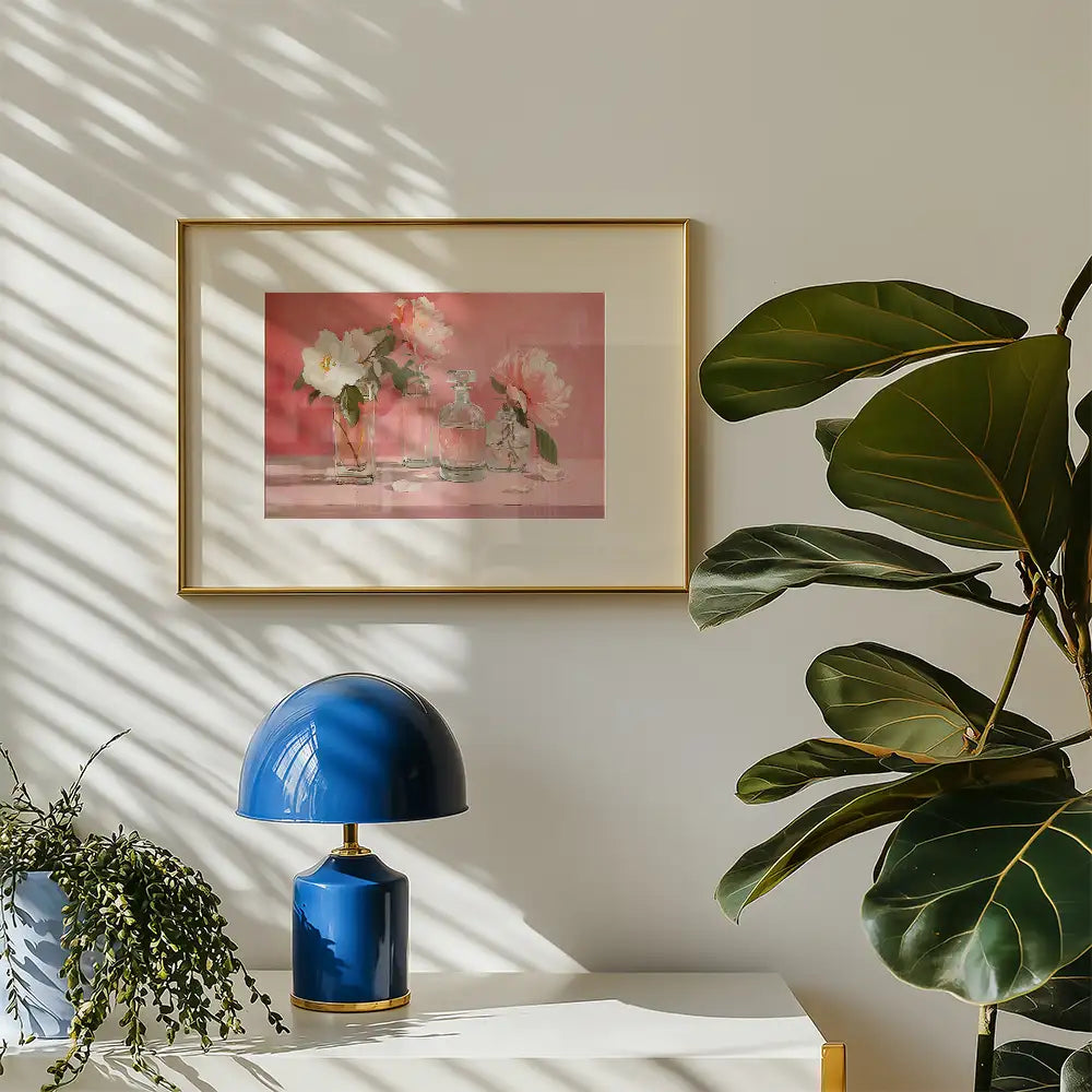 Framed painting of floral still life with glass vases on a pink background, accompanied by a blue lamp and greenery in a modern setting.