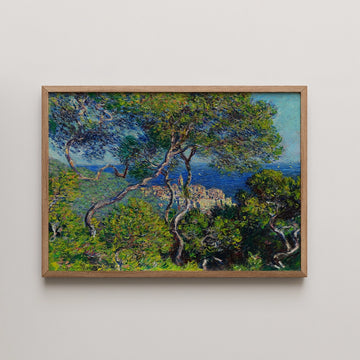 Painting of a lush landscape featuring green trees and a blue sea in the background, framed in a light wooden frame.