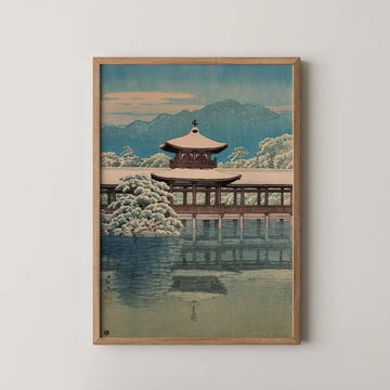 Framed painting of a traditional Asian pavilion surrounded by snow-covered trees, reflecting in still water, with mountains in the background and a pastel sky.