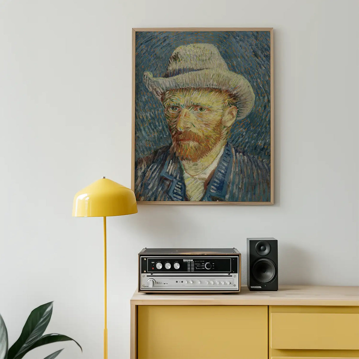 Portrait painting of a bearded man wearing a hat, framed and displayed on a wall above a yellow lamp and vintage audio equipment.