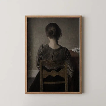 Framed painting of a woman sitting with her back to the viewer, depicting a muted color palette and a sense of solitude.