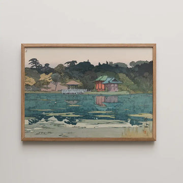 Framed painting of a serene lakeside scene featuring a traditional building, a gazebo, and lush greenery reflected in the water.