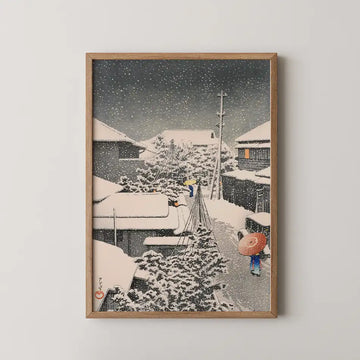 Framed painting depicting a snowy village scene with figures walking, traditional houses, and falling snowflakes.