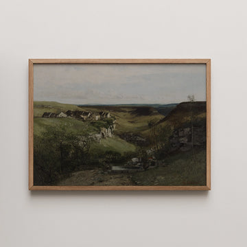 Framed landscape painting showcasing a serene view of rolling hills and rocky cliffs with a distant village under a cloudy sky.