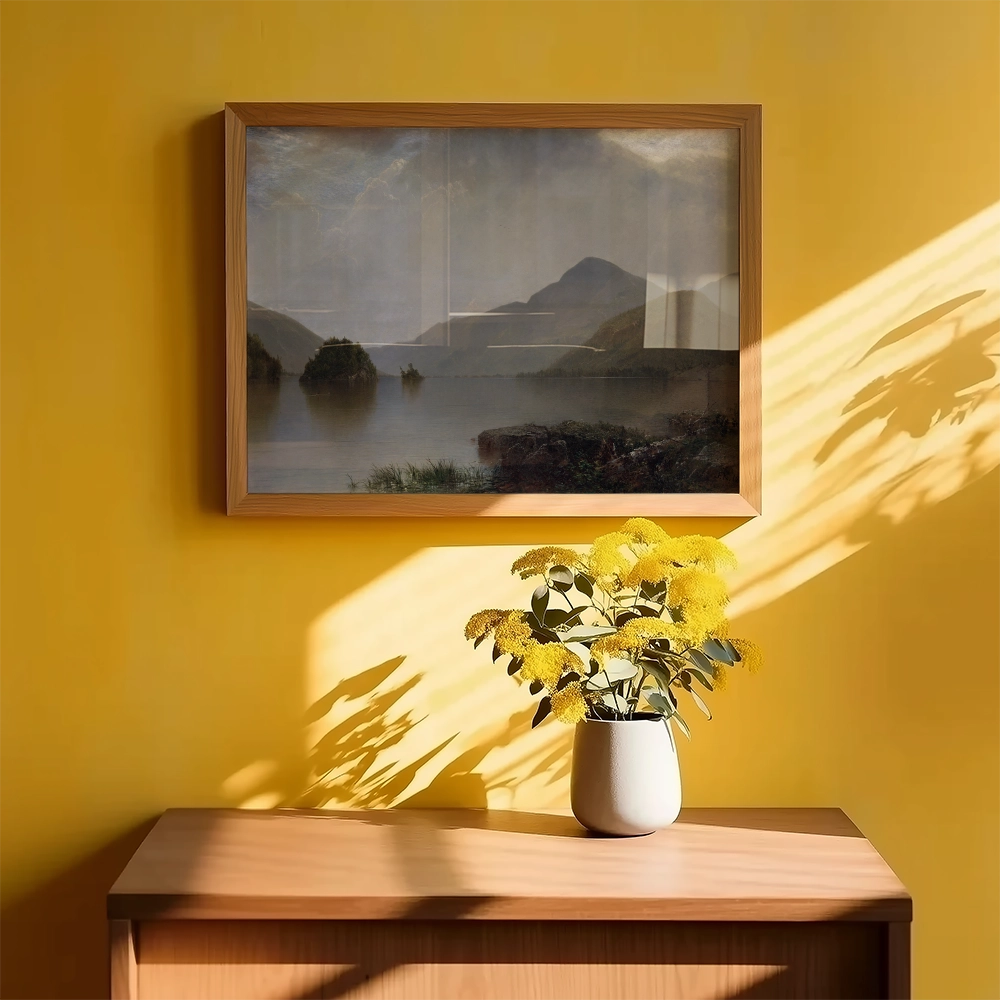 Landscape painting in a wooden frame hanging on a yellow wall, with a vase of yellow flowers on a wooden table in the foreground.
