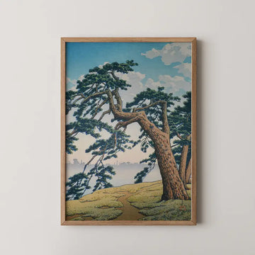 Framed painting of a landscape featuring trees and a winding path leading towards a body of water under a blue sky with clouds.